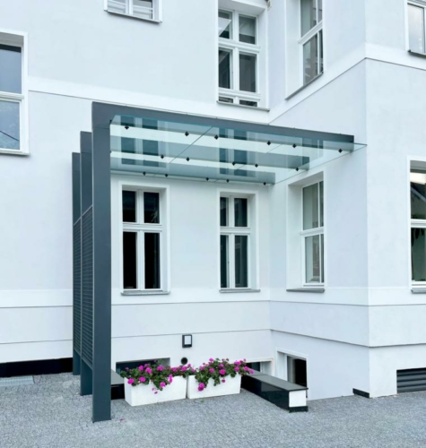 Zadaszenie ze stali, szkła hartowanego i siatki przy zabytkowej kamienicy - KIM Ogrodzenia Budzyń