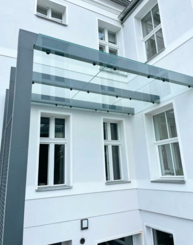 Zadaszenie ze stali, szkła hartowanego i siatki przy zabytkowej kamienicy - KIM Ogrodzenia Budzyń