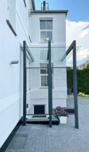 Zadaszenie ze stali, szkła hartowanego i siatki przy zabytkowej kamienicy - KIM Ogrodzenia Budzyń